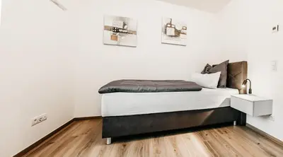 a bed in a room with white walls and wooden floors at Suite by Silvy in Vipiteno