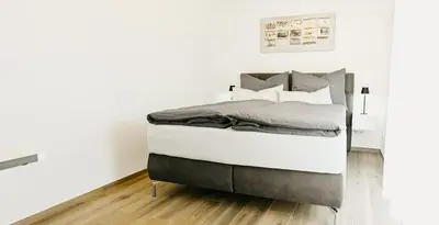 a bed in a room with white walls at Suite by Silvy in Vipiteno