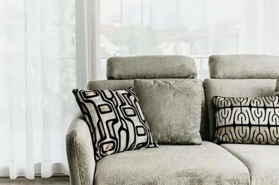 a couch with two pillows sitting next to a window at Suite by Silvy in Vipiteno