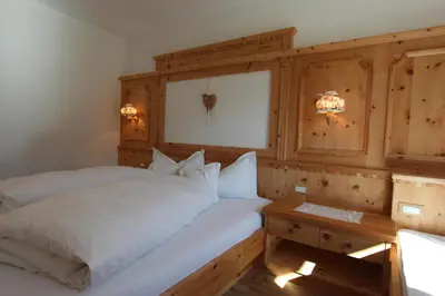 a bedroom with a white bed and a wooden wall at Apartments DAMONT in Santa Cristina in Val Gardena