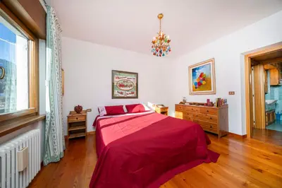 a bedroom with a red bed and a window at Ciasa Marian 10 minutes from Cortina with free parking! in Borca di Cadore