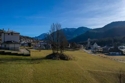 a field with a tree in the middle of a town at Ciasa Marian 10 minutes from Cortina with free parking! in Borca di Cadore