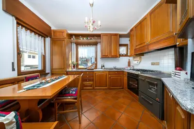 a kitchen with wooden cabinets and a wooden table at Ciasa Marian 10 minutes from Cortina with free parking! in Borca di Cadore