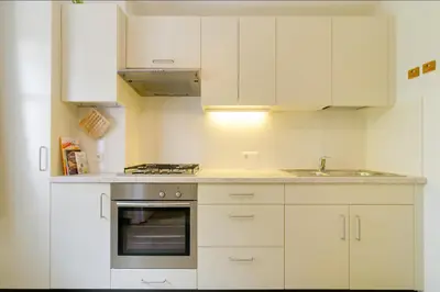 a kitchen with white cabinets and a sink and an oven at Apartment Laura in Ortisei