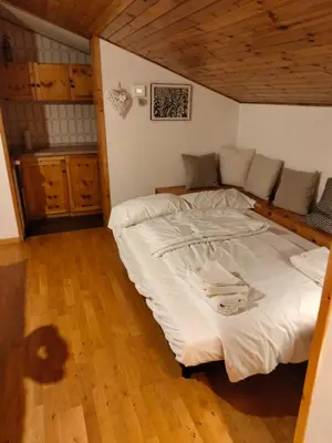 a large white bed in a room with wooden floors at VAL DI FASSA CENTRAL HOUSE - Rooms with free parking in Canazei