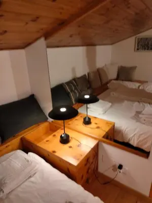 a room with two beds and a table with two lamps at VAL DI FASSA CENTRAL HOUSE - Rooms with free parking in Canazei