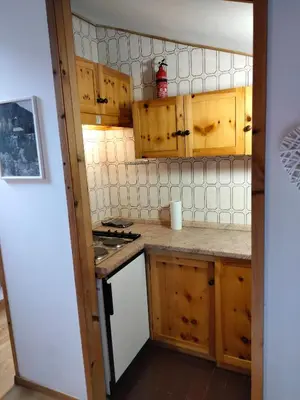 a kitchen with wooden cabinets and a stove top oven at VAL DI FASSA CENTRAL HOUSE - Rooms with free parking in Canazei