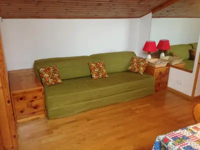 a green couch in a living room with two lamps at VAL DI FASSA CENTRAL HOUSE - Rooms with free parking in Canazei