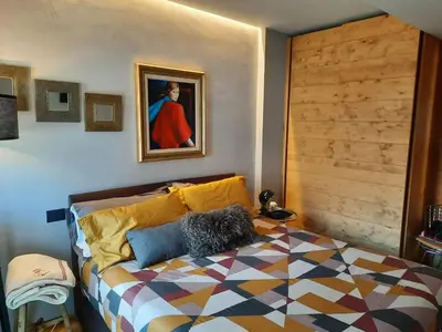 a bedroom with a bed and a painting on the wall at Esclusivo soggiorno a Cortina d'Ampezzo in Cortina dʼAmpezzo