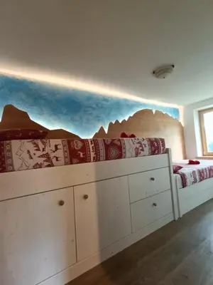 a bedroom with a bed with a mountain mural on the wall at Casa Soraya 2 in Falcade