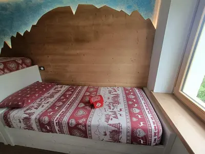 a bed with a wooden headboard in a room at Casa Soraya 2 in Falcade