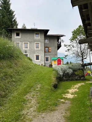 a house on top of a grassy hill at Casa Soraya 2 in Falcade
