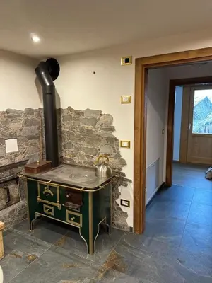 a stove in a room with a stone wall at Casa Soraya 2 in Falcade