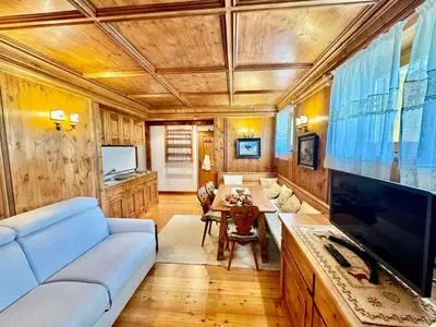 a living room with a blue couch and a tv at Ca del Rio - Cortina in Cortina dʼAmpezzo