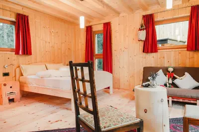 a bedroom with a bed and a chair in a room at Forest Chalet Resort FELIZITAS in San Felice