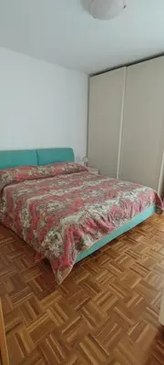 a bedroom with a bed and a wooden floor at Appartamenti Donatella in Cavalese
