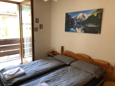 a bedroom with a bed and a large window at Casa Solidea in Moena