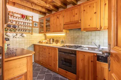 a kitchen with wooden cabinets and a stove top oven at Casa Scoiattolo, con balcone panoramico in San Vito di Cadore