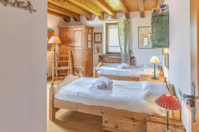 two beds in a room with wooden floors and ceilings at Casa Scoiattolo, con balcone panoramico in San Vito di Cadore