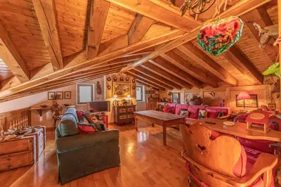 a large living room with wooden ceilings and a table at Casa Scoiattolo, con balcone panoramico in San Vito di Cadore