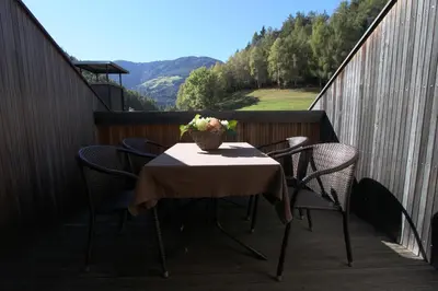 a table and chairs on a balcony with a vase of flowers at Ferienwohnung Pirchner in San Lorenzo di Sebato