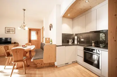 a kitchen with white cabinets and a table and chairs at Moarhof Albeins in Albes