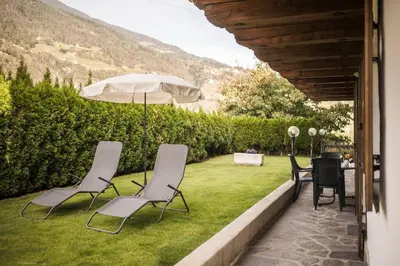 a patio with a table and chairs and an umbrella at Moarhof Albeins in Albes