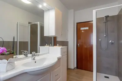 a white bathroom with a sink and a shower at Dolomiapartments - Appartamento Centrale in Predazzo