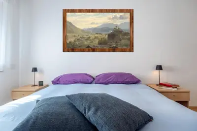 a bedroom with a bed with a painting on the wall at Dolomiapartments - Appartamento Centrale in Predazzo