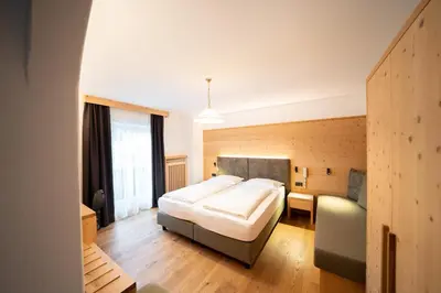 a bedroom with a large bed and a couch at Hotel Ortler in Castelrotto