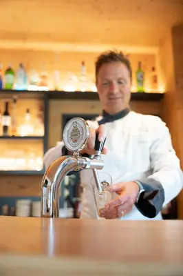 a man in a kitchen pouring a drink at Hotel Ortler in Castelrotto