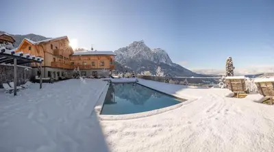 a swimming pool covered in snow next to a building at Hotel Ortler in Castelrotto