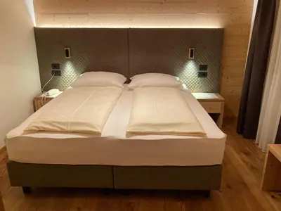 a bedroom with a large bed with white sheets and pillows at Hotel Ortler in Castelrotto