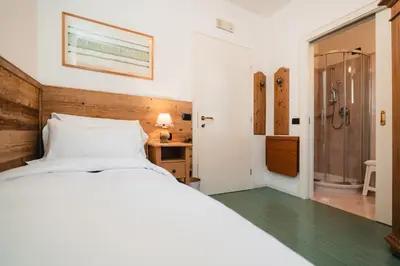 a bedroom with a white bed and a shower at Hotel Oasi in Cortina dʼAmpezzo