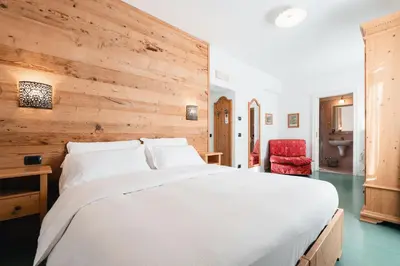 a bedroom with a white bed and a wooden wall at Hotel Oasi in Cortina dʼAmpezzo