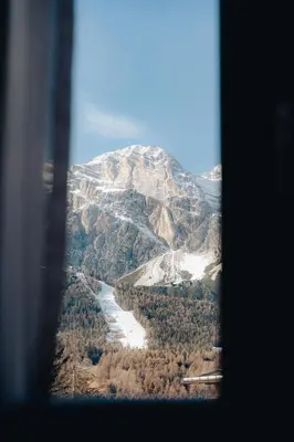 a view of a snowy mountain from a window at Hotel Oasi in Cortina dʼAmpezzo
