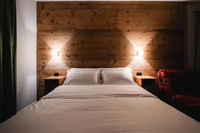 a bedroom with a bed with two night stands at Hotel Oasi in Cortina dʼAmpezzo