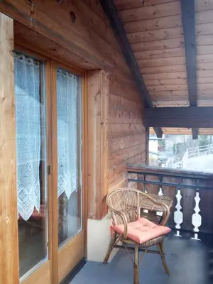 a chair sitting on a porch with a window at Digart apartment in Ortisei