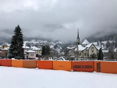 a town in the snow with a church at 1500-year-old El Molin Cottage in the heart of Moena in Moena