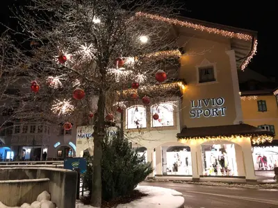 a lit up building with christmas lights on a tree at 1500-year-old El Molin Cottage in the heart of Moena in Moena