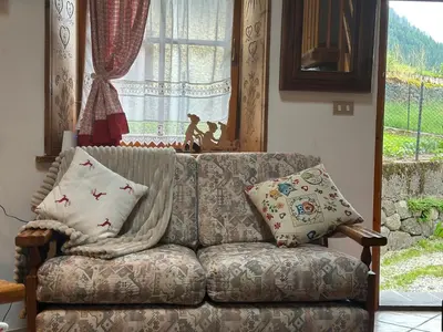 a couch sitting in a living room with a window at 1500-year-old El Molin Cottage in the heart of Moena in Moena