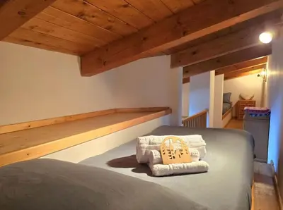 a bedroom with a bed in a room with wooden ceilings at 1500-year-old El Molin Cottage in the heart of Moena in Moena