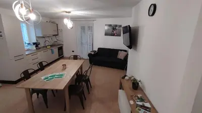 a kitchen and a living room with a table and a couch at La casa di Nicole in Romeno