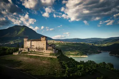 a castle on a hill next to a body of water at La casa di Nicole in Romeno