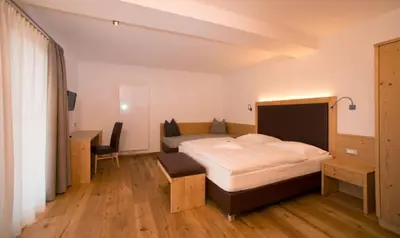 a bedroom with a bed and a desk and a bed sidx sidx sidx at Pension Grohmann in Santa Cristina in Val Gardena