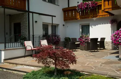 a patio of a building with chairs and flowers at Pension Grohmann in Santa Cristina in Val Gardena