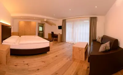 a bedroom with a large bed and a desk at Pension Grohmann in Santa Cristina in Val Gardena