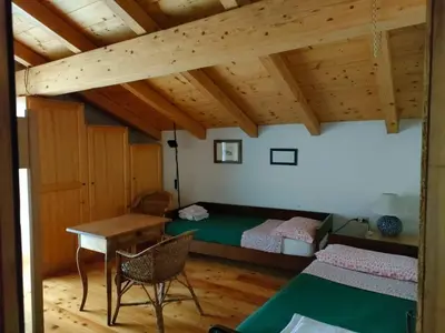 a bedroom with a bed and a desk and a table at Appartamento Maso Tati in Predazzo