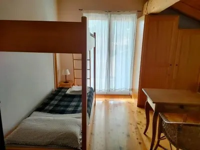 a bedroom with a bunk bed and a table and a desk at Appartamento Maso Tati in Predazzo