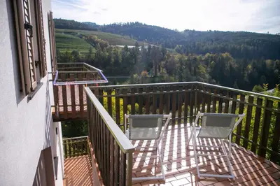 a balcony with two chairs and a view of a valley at Casa Maia in Sanzeno